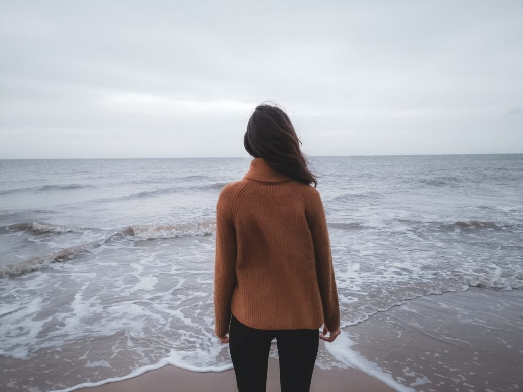 a woman standing on a beach looking out at the ocean